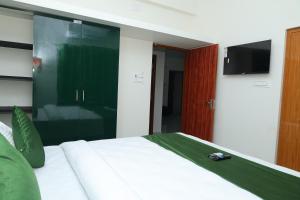 a bedroom with a bed with a tv on the wall at Skytouch Residency-OMR in Chennai