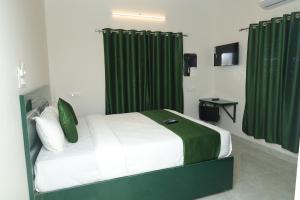 a bedroom with a bed with green curtains at Skytouch Residency-OMR in Chennai