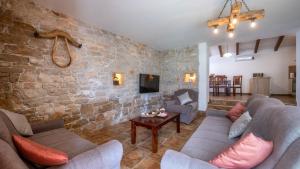 a living room with two couches and a stone wall at Villa Katja by Villas Guide in Peruški