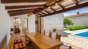a dining room with a wooden table and a swimming pool at Villa Katja by Villas Guide in Peruški