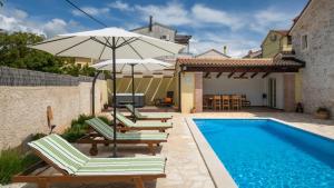 a pool with chairs and an umbrella next to a house at Villa Katja by Villas Guide in Peruški