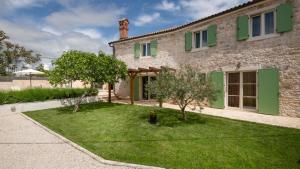 a stone house with green shutters and a yard at Villa Katja by Villas Guide in Peruški