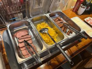 a tray of food with meat and eggs and sausages at Santana Lodge Hakuba in Hakuba