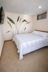 a bedroom with a white bed with a plant on the wall at El Jardín cerca Aeropuerto de Pasto, comodidad y descanso in Chachagüí