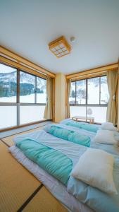 a room with four large beds in front of windows at Yuzawa YUKITORA 雪虎 in Minami Uonuma