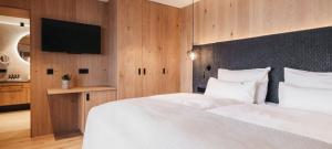 a bedroom with a white bed and a television at Hotel Oberforsthof in Sankt Johann im Pongau