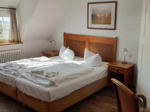 a bedroom with a bed with white sheets and pillows at Hotel Hiddensee Hitthim in Kloster