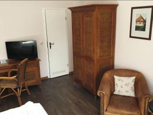 a room with a television and a chair and a desk at Hotel Hiddensee Hitthim in Kloster
