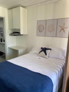 a bedroom with a white bed with a blue blanket at Flat Garden 02-A - Beach Class Verano - Porto de Galinhas in Ipojuca