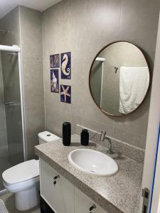 a bathroom with a sink and a toilet and a mirror at Flat Garden 02-A - Beach Class Verano - Porto de Galinhas in Ipojuca