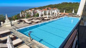 a large swimming pool with chairs and the ocean at Arabela 2 Apartments in Utjeha