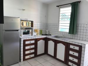 a kitchen with a stainless steel refrigerator and a microwave at Résidence Le Lagon in Sainte-Anne