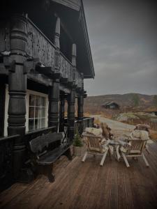 a wooden deck with two benches and a building at Great mountain cabin with 12 beds in Vågsli