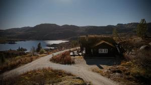 a house on a dirt road next to a lake at Great mountain cabin with 12 beds in Vågsli