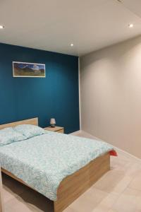 a bedroom with a bed with a blue wall at La croix majot in Regniowez