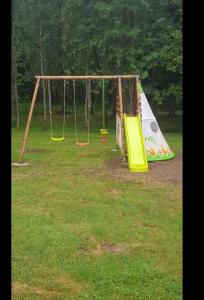a park with a swing set in the grass at La croix majot in Regniowez