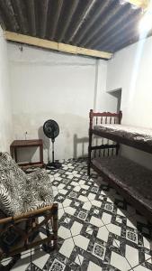a room with a bed and a chair and a tiled floor at Casa da Biza 1 in Cananéia