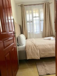 a bedroom with a bed and a window at Stylish 1br Milimani in Kisumu