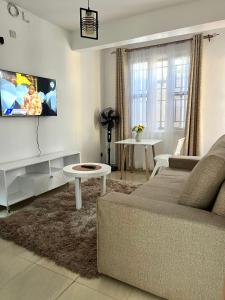a living room with a couch and a tv on the wall at Stylish 1br Milimani in Kisumu