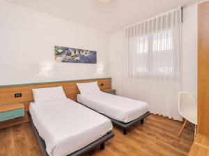 a room with two beds and a window at B&B HOTEL Eurorest Conegliano in Conegliano