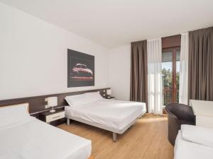 a hotel room with two beds and a window at B&B HOTEL Eurorest Conegliano in Conegliano