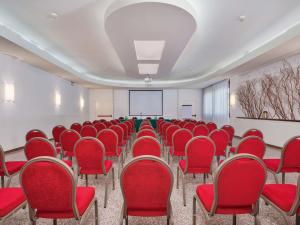 an empty room with red chairs and a projection screen at B&B HOTEL Eurorest Conegliano in Conegliano +24 photos
