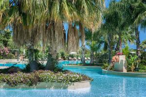 a swimming pool with palm trees in a resort at Acacia Resort in Campofelice di Roccella