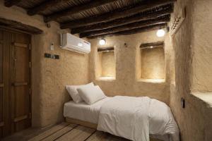 a bedroom with a bed with white sheets and windows at بيت العريش Arish house in Sayq