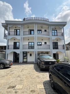 a large white building with cars parked in front of it at SLAR Résidence in Douala