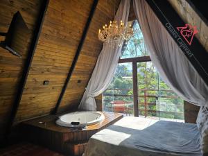 a bathroom with a tub in a room with a window at Chale Capivari Estrela in Campos do Jordão