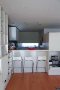 a kitchen with white cabinets and white bar stools at Bloom - Beach House in Apúlia
