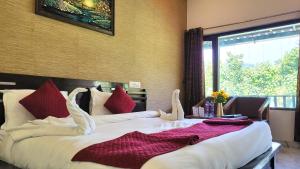 a bedroom with two beds with white sheets and red pillows at Corbett Nature Walk - Forest View Swimming Pool Retreat in Rāmnagar
