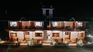 a large white building with a balcony at night at Corbett Nature Walk - Forest View Swimming Pool Retreat in Rāmnagar