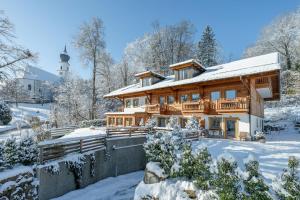 a log home in the snow with a lighthouse at Landhotel Berger in Ainring