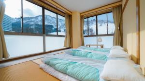 three beds in a room with large windows at Yuzawa YUKITORA 雪虎 in Minami Uonuma