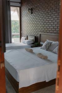 two beds in a bedroom with a brick wall at Django Villa Weligama in Weligama