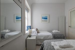 a white room with two beds and a mirror at Bakers Close - Elie in Elie