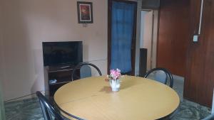 a wooden table with a vase of flowers on it at Graciana Quequén in Necochea