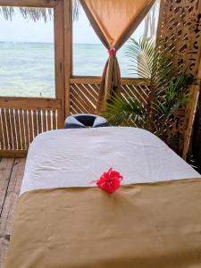 a bed in a room with a view of the ocean at Lala Land Lodge in Kizimkazi