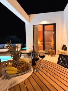 a table with a plate of fruit and wine glasses at Kudos Luxury villas in Korinthos
