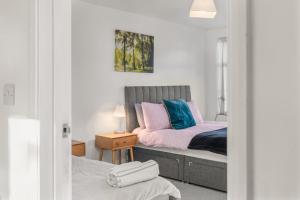 a bedroom with a bed with pink and blue pillows at Badger Haven, Apartment 2 in Brackley