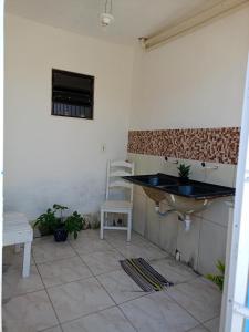 a bathroom with a sink and a chair in a room at Hospedaria D' Gabi in São Pedro da Aldeia