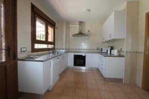 a kitchen with white cabinets and a tile floor at Casa Jardin del Valle. TuCasaTemporal in Seseña