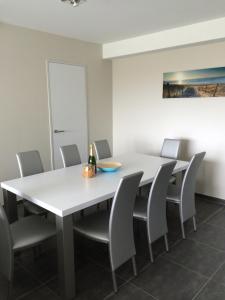 une salle à manger avec une table et des chaises blanches dans l'établissement Karthuizer Zeezicht I, à Nieuport