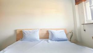 a bed with white sheets and pillows in a room at Casa completa - Camiño dos faros - Atlantico Malpica in Malpica