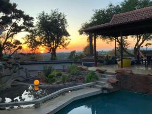a backyard with a pool with a sunset in the background at Oasis On Lily with OWN Pool in Johannesburg