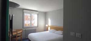 a bedroom with a white bed and a window at Logis Hotel Restaurant Le Cygne in Yssingeaux