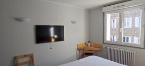 a bedroom with a bed and a television on the wall at Logis Hotel Restaurant Le Cygne in Yssingeaux