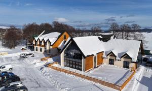 a building covered in snow with cars parked in a parking lot at Hotel Nordik in Žabljak