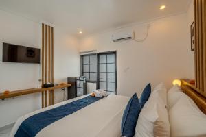 a bedroom with a large white bed with blue pillows at Little Soho Pererenan in Canggu